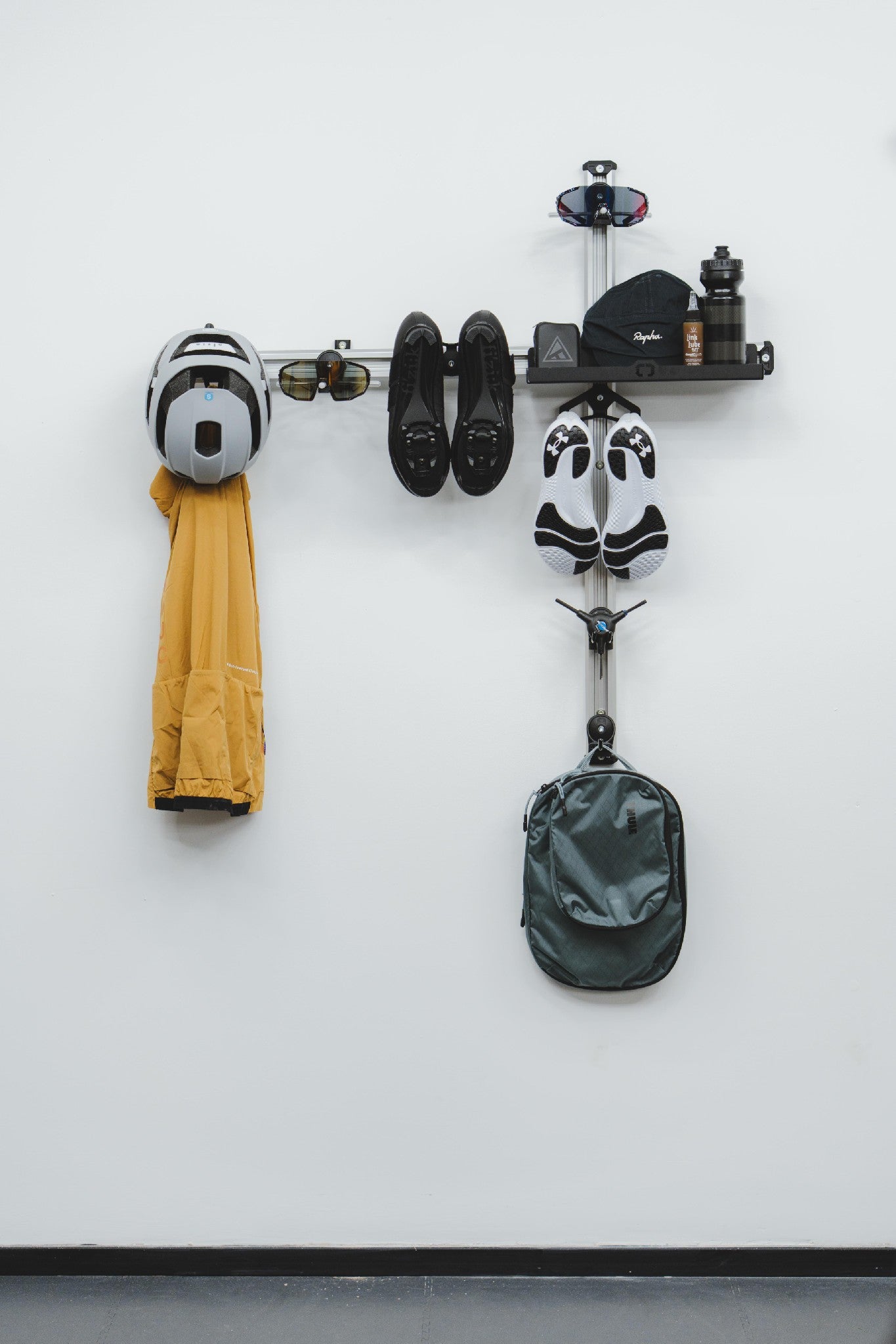 Wall-mounted bike rack with helmet, coat, and backpack on a white wall