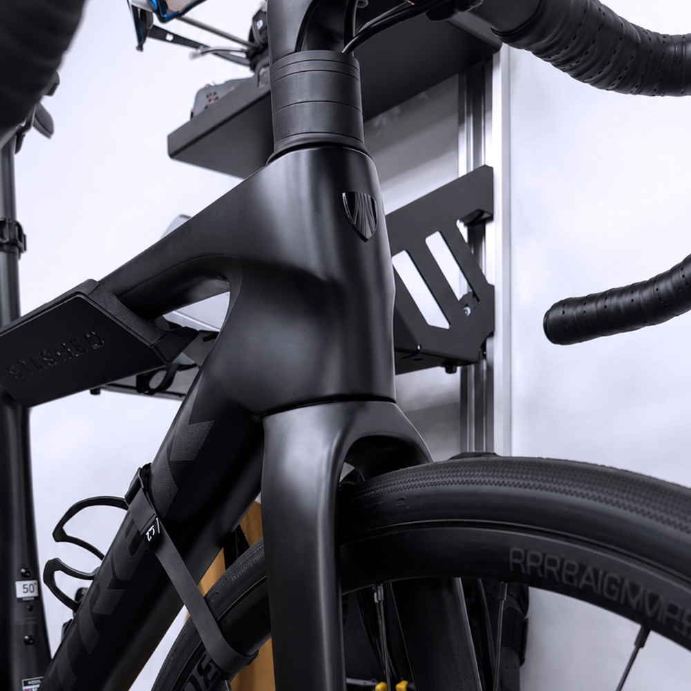 Road bike stored on the rail mounted SpaceRail ONE Pro Set with cycling kit on the rails